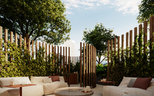Outdoor lounge with beige sectional sofas, a circular fire pit table, and tall wooden slats surrounded by trees under a blue sky.