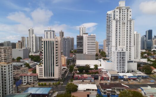 20200604_104430 - Panama Elite Homes City skyline with white high-rise buildings under a blue sky, viewed from street level.