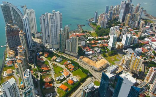 Aerial view of a coastal city with numerous high-rise condos and a bright blue bay nearby.