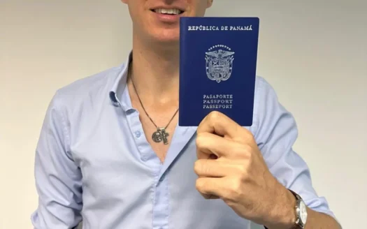 Man holds a blue Panama passport up to camera, shirt and necklace visible, passport text clear: República de Panamá / Pasaporte.