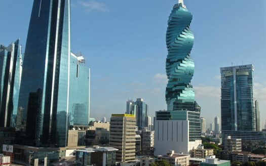 Bangkok skyline with a twisting green high-rise (King Power Mahanakorn) against a blue sky.